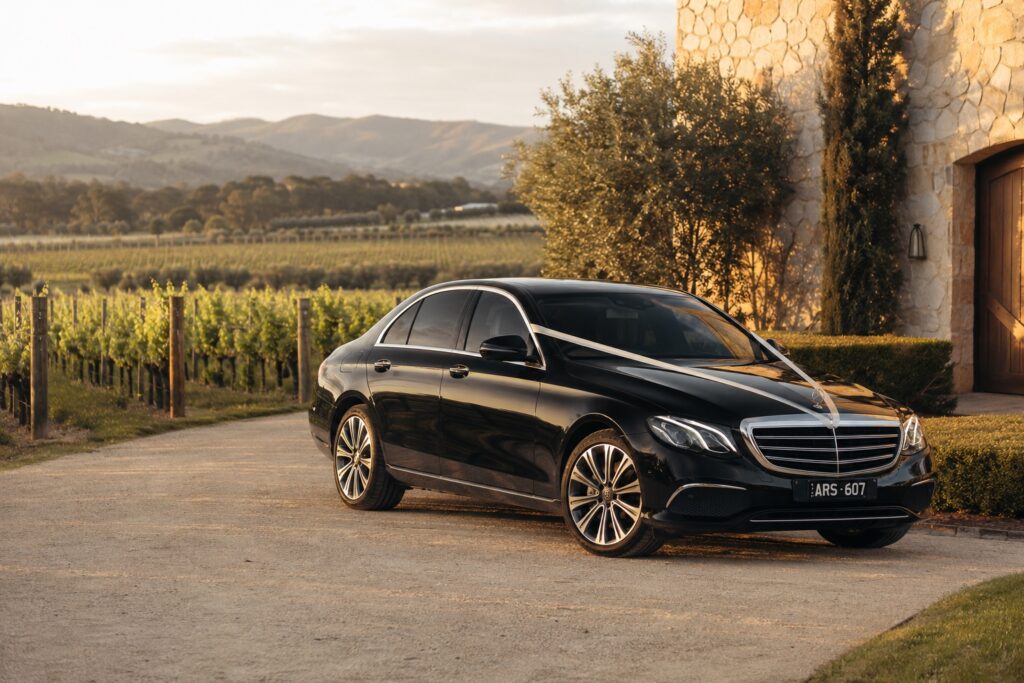 Black Pro Limo Mercedes-Benz wedding car with ivory ribbon at a Yarra Valley vineyard